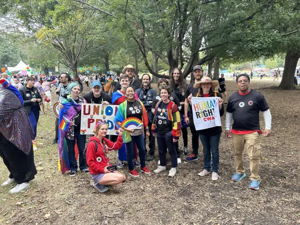 Image showing about a dozen people posed for a photograph at 2023 Atlanta Pride. The people in the picture are wearing lots of rainbow colors.